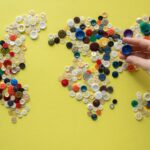 Colorful world map crafted from assorted buttons on a vibrant yellow background.