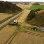 Aerial view of a combine and tractor harvesting a wheat field in Lemvig, Denmark.