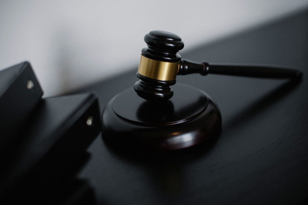 High angle of shiny wooden ceremonial mallet with golden detail placed on judge tale near documents folders
