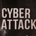 Text 'Cyber Attack' on textured dark paper highlights digital security threat concept.