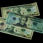 High angle view of US 10 and 20 dollar bills on a black background, emphasizing finance and currency themes.