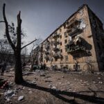 A war-torn residential building in Kyiv, Ukraine, showing significant destruction and debris.