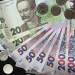 Close-up of assorted Ukrainian banknotes and coins on a dark background.