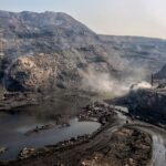 A dramatic aerial view of a coal mine in Dhanbad, Jharkhand, India showcasing rugged landscapes and mining activity.