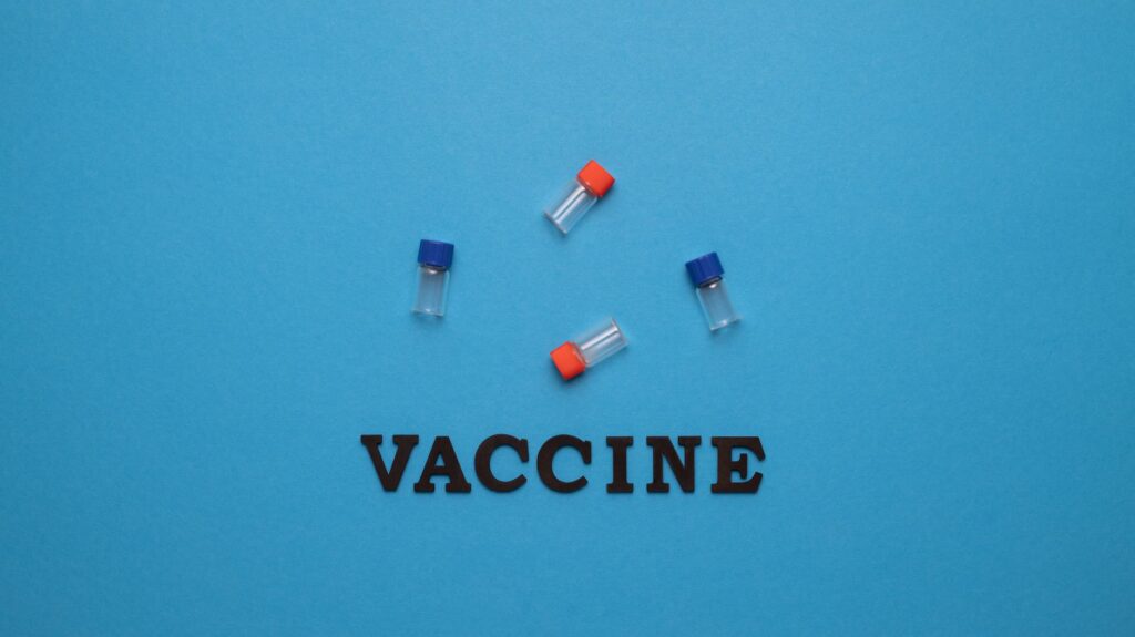 Three small vials and the word 'VACCINE' on a blue background, representing vaccination and health.
