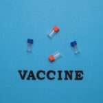 Three small vials and the word 'VACCINE' on a blue background, representing vaccination and health.