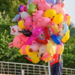 Vibrant cartoon character balloons being sold outdoors on a sunny day in a park.