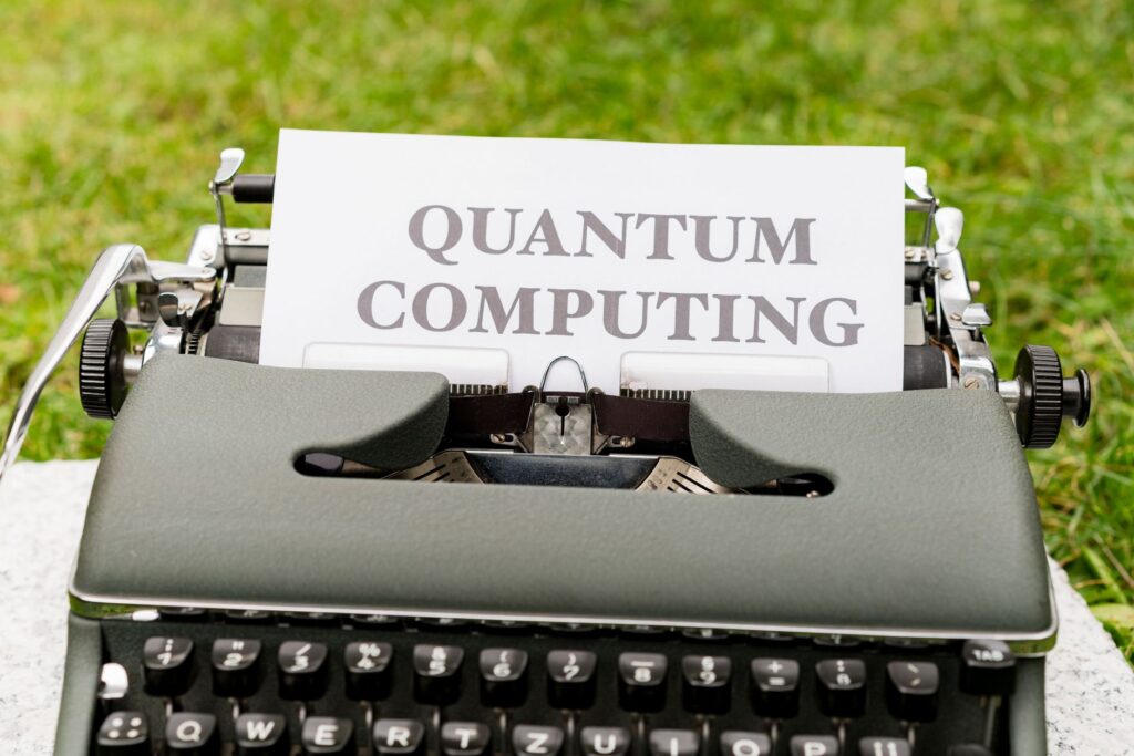 A typewriter with 'Quantum Computing' text outdoors on grass, blending old and new technologies.