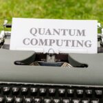 A typewriter with 'Quantum Computing' text outdoors on grass, blending old and new technologies.