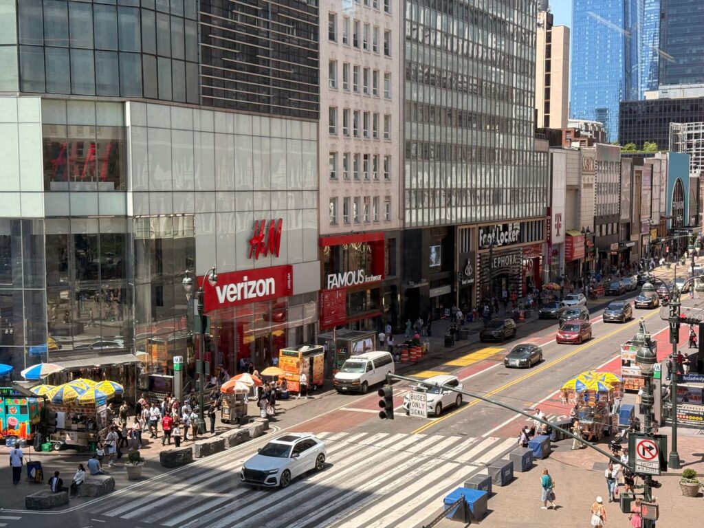 Busy day in Midtown Manhattan with pedestrians and traffic on a sunny afternoon.