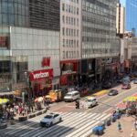 Busy day in Midtown Manhattan with pedestrians and traffic on a sunny afternoon.