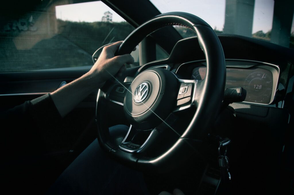 Close-up view of a driver's hands on a Volkswagen steering wheel in a moving car.