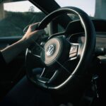 Close-up view of a driver's hands on a Volkswagen steering wheel in a moving car.