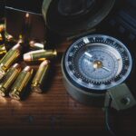 Close-up of brass bullets scattered around a vintage compass on a wooden surface, conveying exploration.