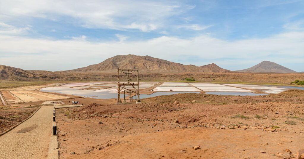 Dry landscape with mountains and salt pans under a clear blue sky.