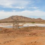 Dry landscape with mountains and salt pans under a clear blue sky.