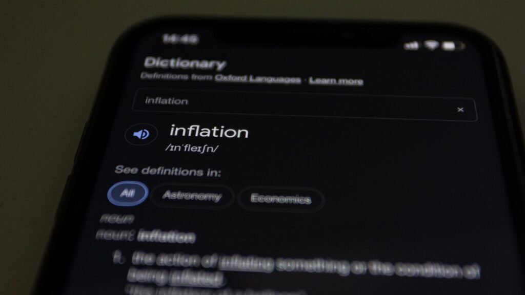 Close-up of a smartphone screen showing the word inflation defined in a dictionary app.