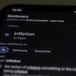 Close-up of a smartphone screen showing the word inflation defined in a dictionary app.