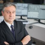 Business executive in office focused on financial analysis with computer monitors.