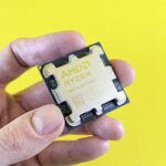 Detailed shot of AMD Ryzen 7 9700X processor held against bright yellow background.