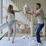 Happy young couple having a playful pillow fight in a cozy living room.