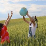Joyful kids holding an earth globe in a lush wheat field, symbolizing global unity.
