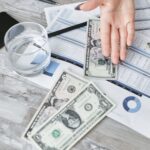 A top view of financial documents with dollar bills and a glass of water, emphasizing budgeting.