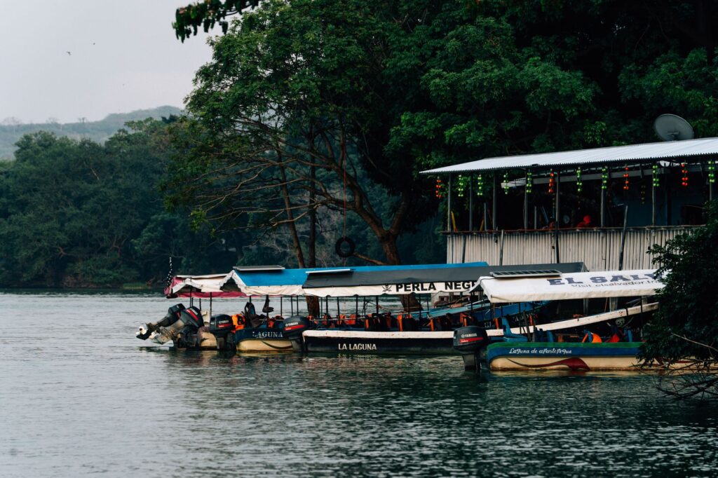 Peaceful riverside setting with boats docked by a colorful, decorated building.