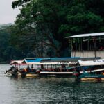 Peaceful riverside setting with boats docked by a colorful, decorated building.