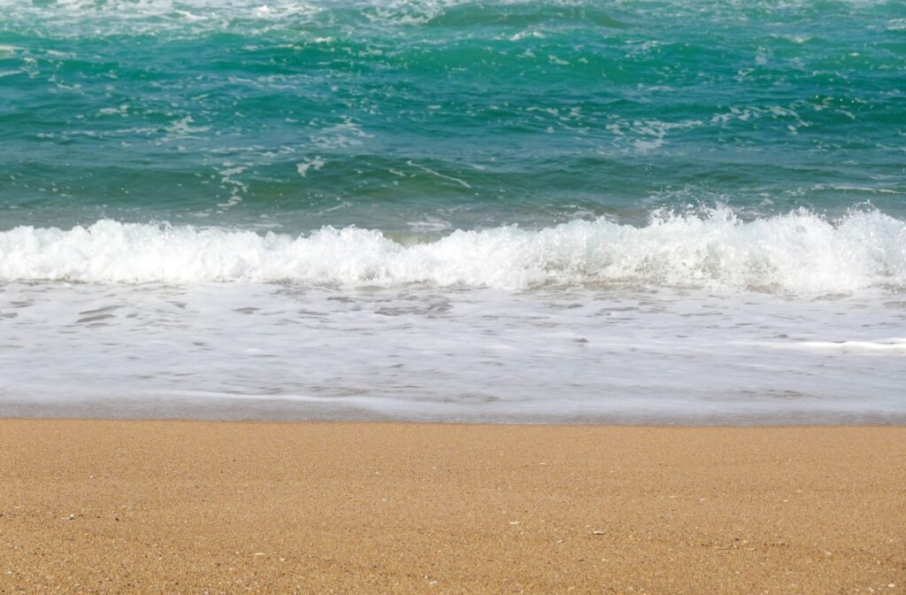 Calm ocean waves gently crash onto a sandy beach, capturing the essence of tranquility.