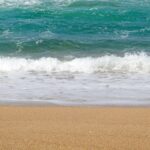 Calm ocean waves gently crash onto a sandy beach, capturing the essence of tranquility.