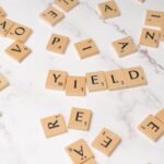 Scrabble tiles forming the word 'YIELD' on a marble surface, symbolizing finance and investment.