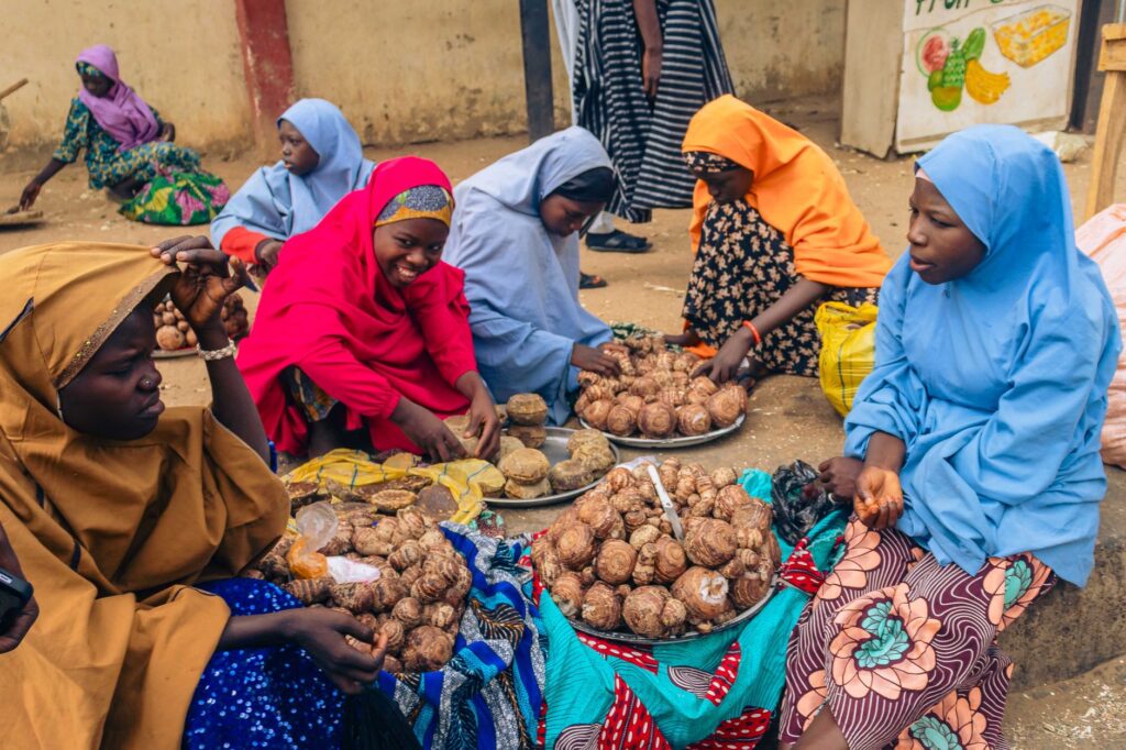 Colorful street market scene with women selling snails in Africa, highlighting cultural traditions.