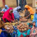 Colorful street market scene with women selling snails in Africa, highlighting cultural traditions.