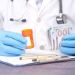 Doctor in gloves holding pill bottle and cash, highlighting medical expenses.