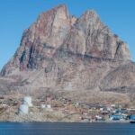 Scenic view of Uummannaq town and soaring mountain cliffs, Greenland.