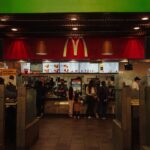A bustling scene at a McDonald's restaurant counter with customers and staff in an indoor setting.