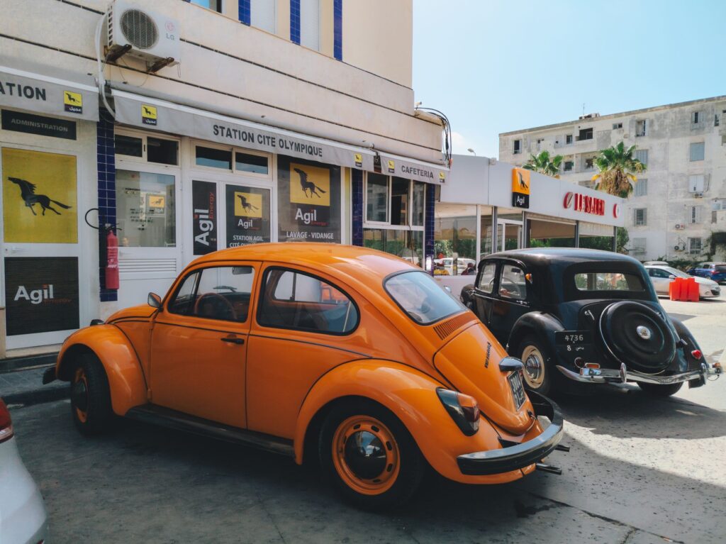 Colorful vintage cars parked at Agil gas station in Tunis, capturing a nostalgic urban scene.