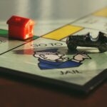 Close-up shot of a Monopoly board game featuring a toy car and a red house on 'Go to Jail'.