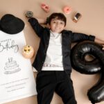 Young boy celebrating his 9th birthday with balloons and treats, lying happily.